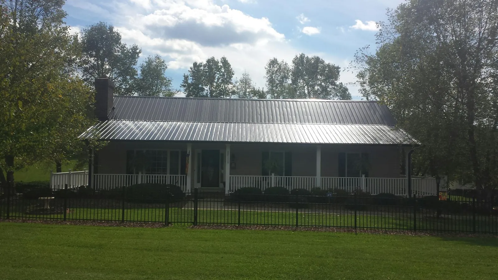 Gray metal roof on a brick ranch with a full width front porch — Gutter Guard Installation work by our crew in Claremont